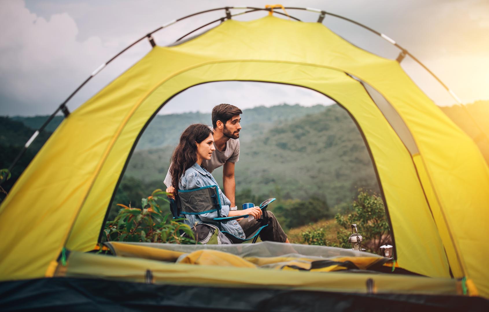 Happy couple man woman sitting chair front camping tent campsite morning with
