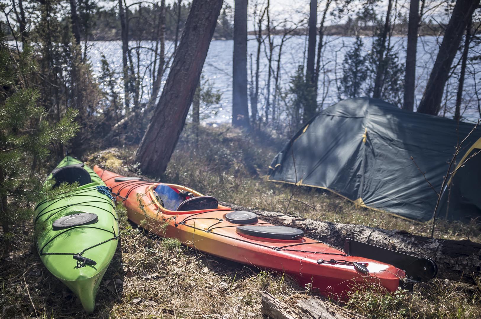 Two kayaks are forest near camp sun smoke from fire near lake