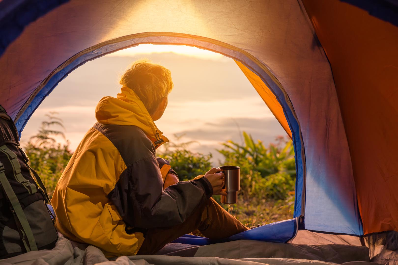 Young man sitting tent with holding coffee cup